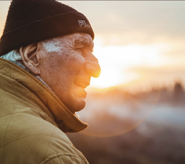 An older man smiling at sunset